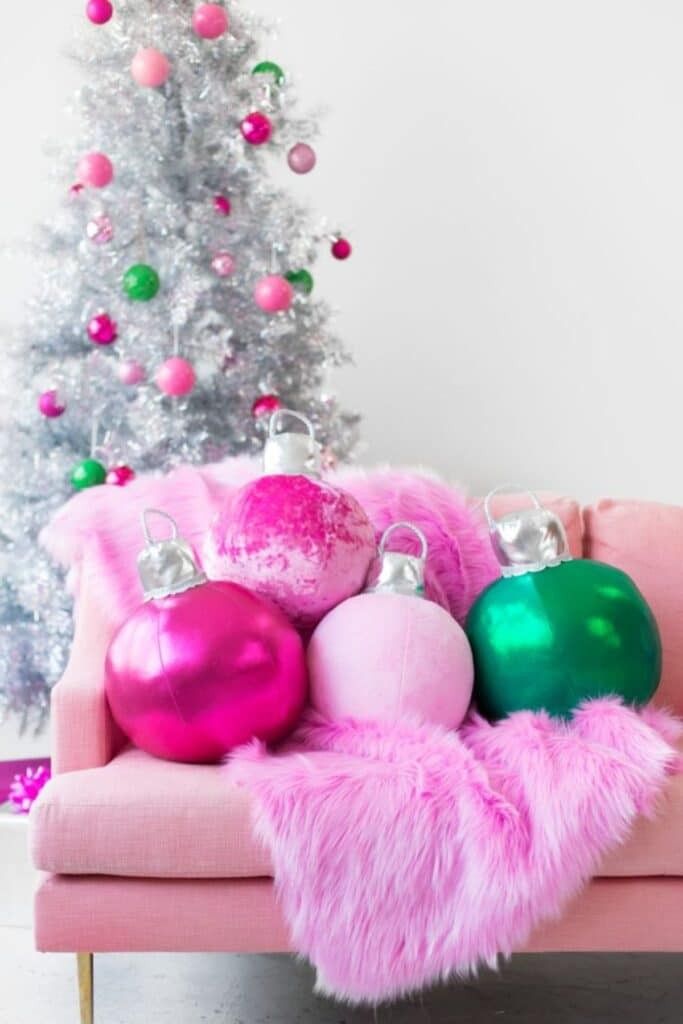 A modern, fluffy pink Christmas tree decorated with gold and silver ornaments.