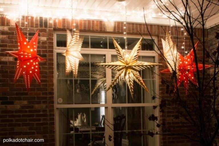 Large paper star-shaped lanterns glowing warmly in a living room window.