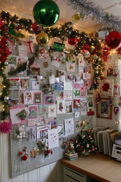 A stack of Christmas cards on a desk with a small tree.
