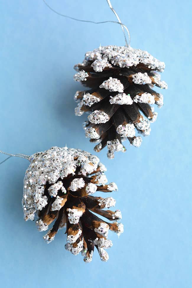 White fireplace mantel styled with felt pom-pom garland natural pinecones soft warm fireplace glow