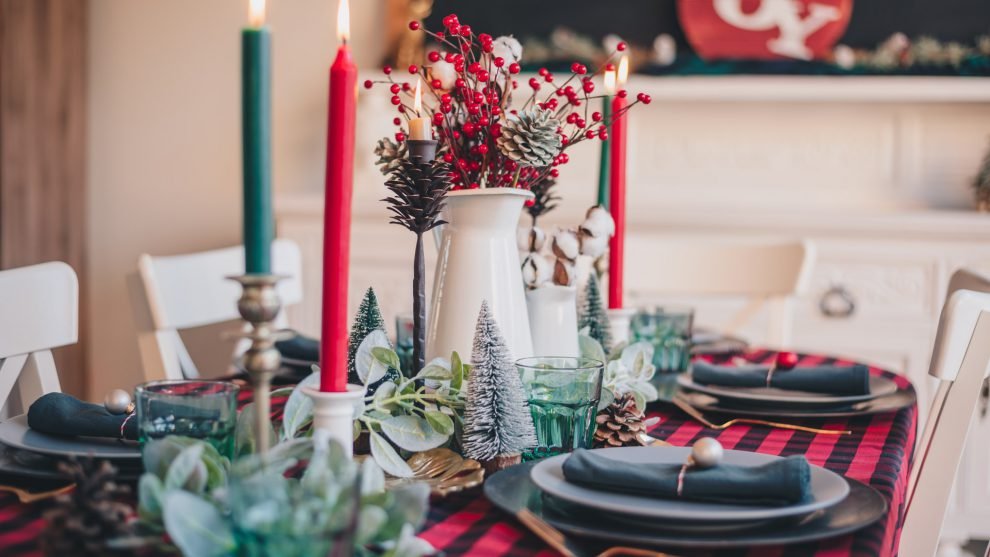 A farmhouse Christmas mantel with pine garlands, brass candlesticks, and wooden stocking holders displayed.
