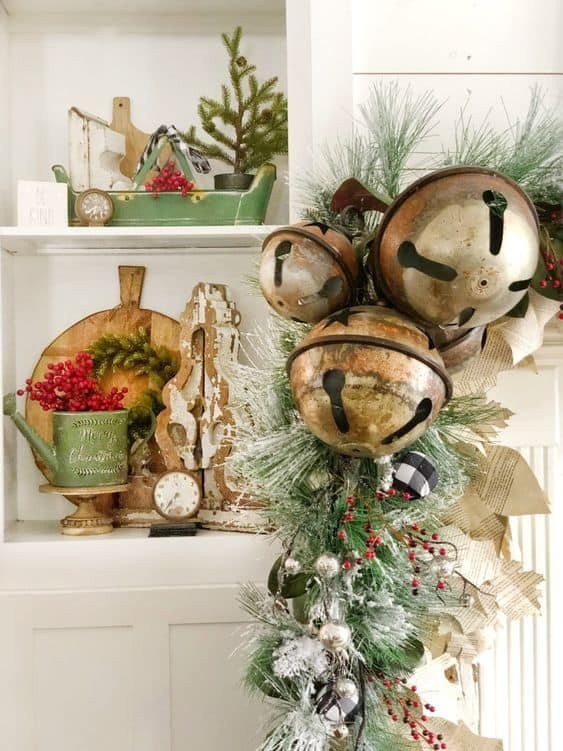 A window framed with a greenery garland, twinkling lights, and hanging star ornaments.
