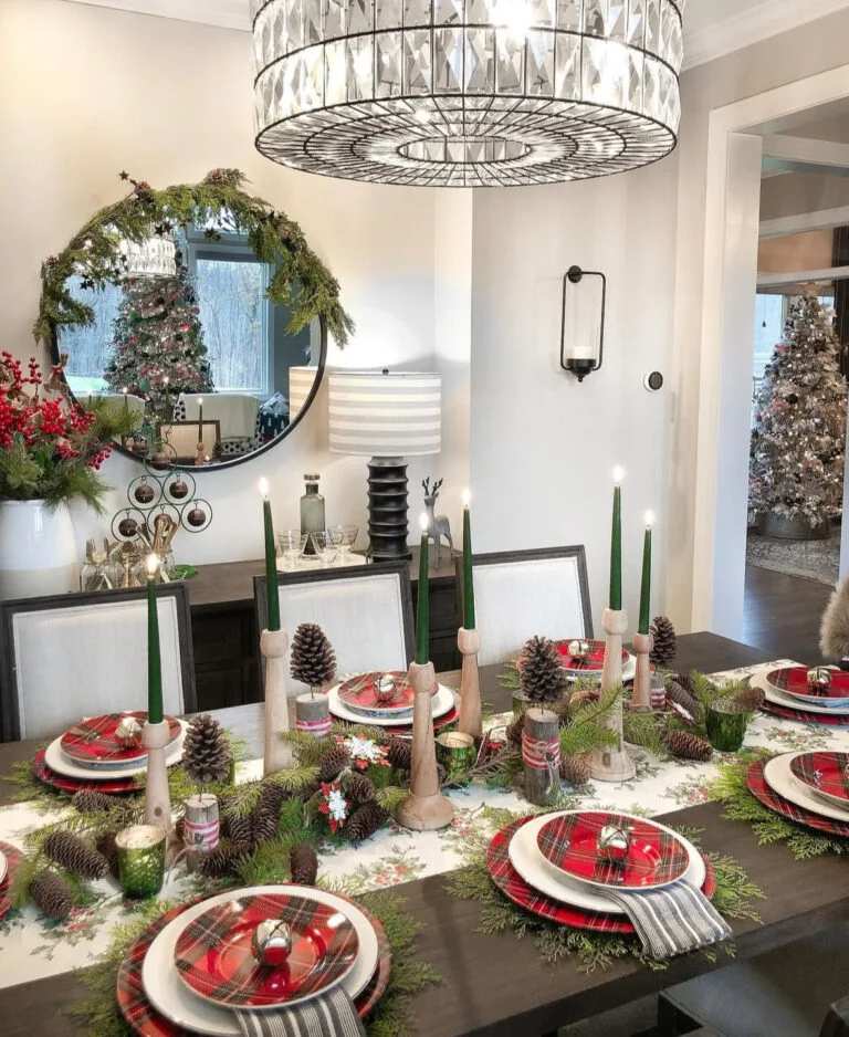 Dining table with plaid plates, green candles, and a pinecone centerpiece.