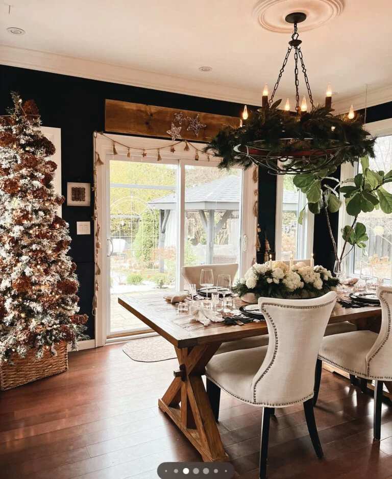 Dining table with rustic pinecone garland and chandelier in a dark room.
