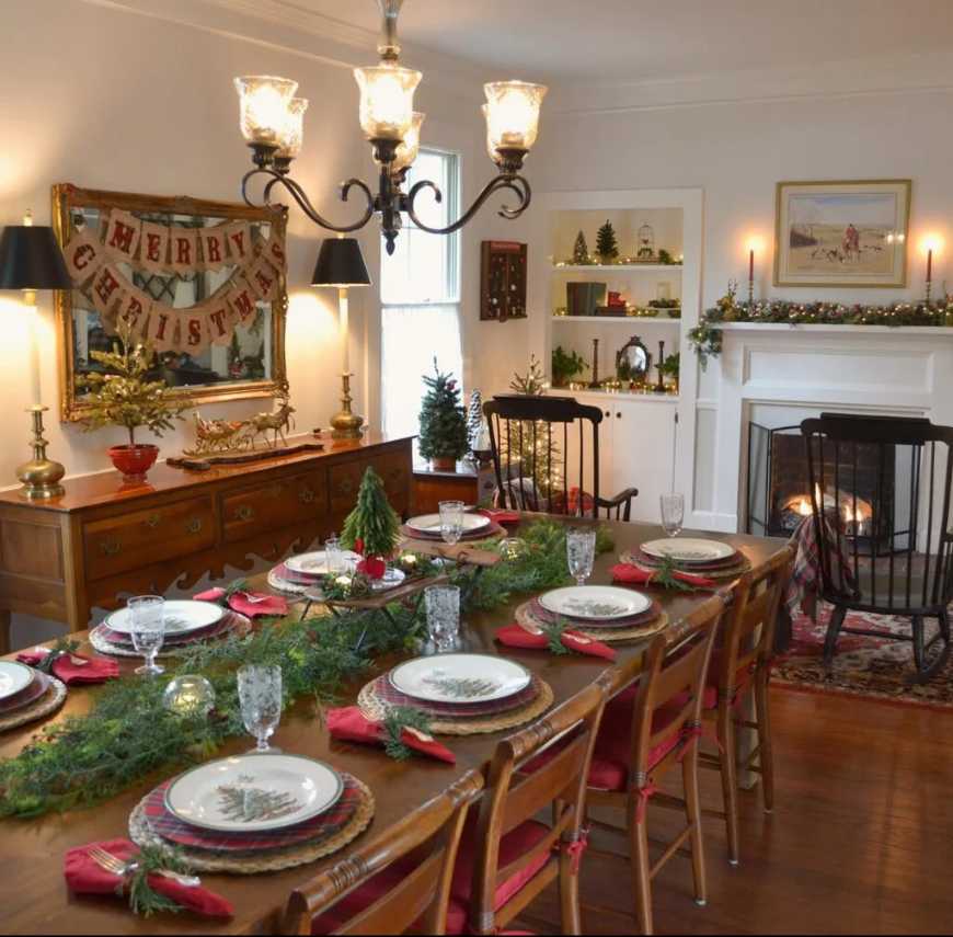 Traditional dining room with lit fireplace, wooden table, and a festive Merry Christmas banner.