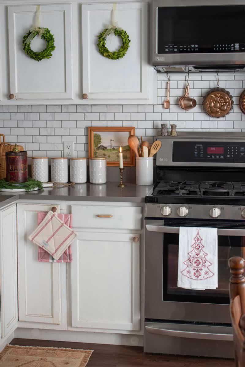 Kitchen with glossy navy cabinets, red striped tie‑backs, brushed nickel hardware, cool LED lighting, festive detail
