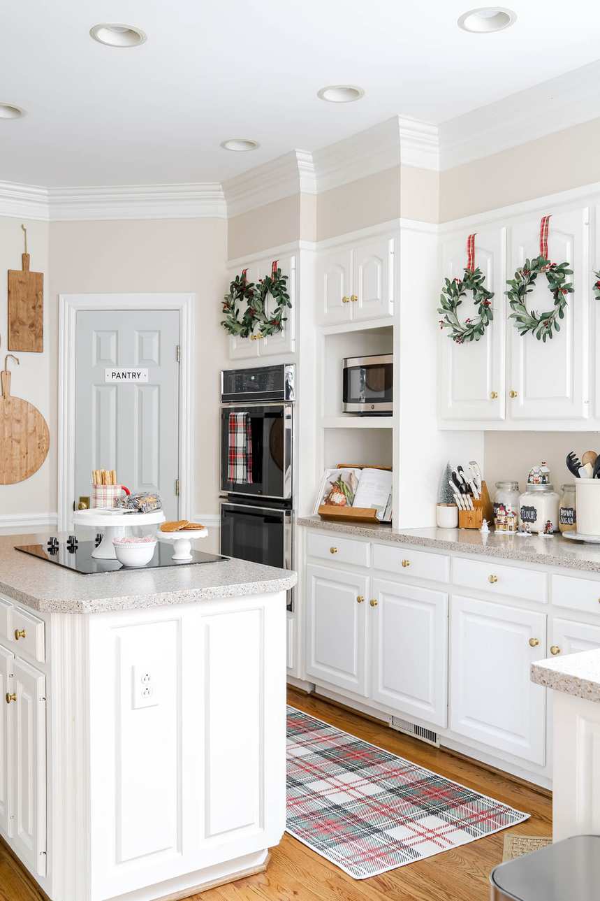 Kitchen with glass‑front cabinets, frosted pine sprig decals, soft pastel lighting, airy festive vibe