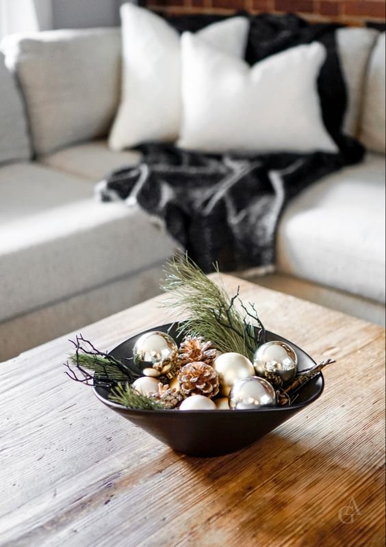 Dining room table centerpiece with glass cloches, metallic ornaments, wood base, warm amber lighting.