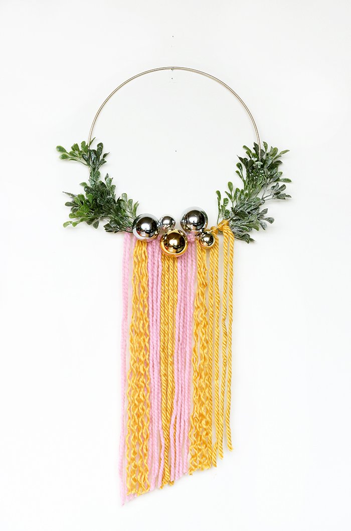 Elegant champagne gold christmas ornament wreath displayed on a white painted interior door with warm ambient hall lighting.