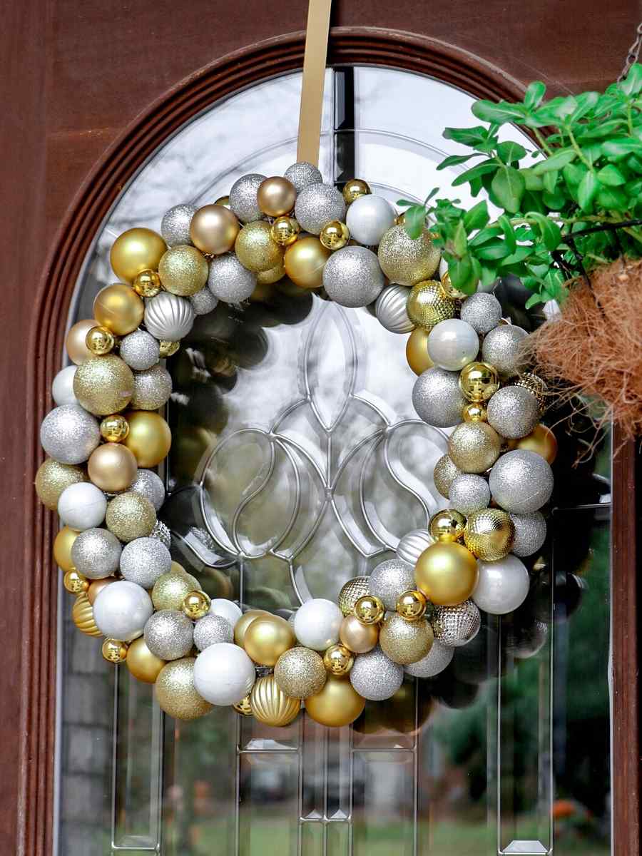 Rustic living room with stone fireplace, matte gold ornament wreath, reclaimed wood mantle, amber ambient lights.
