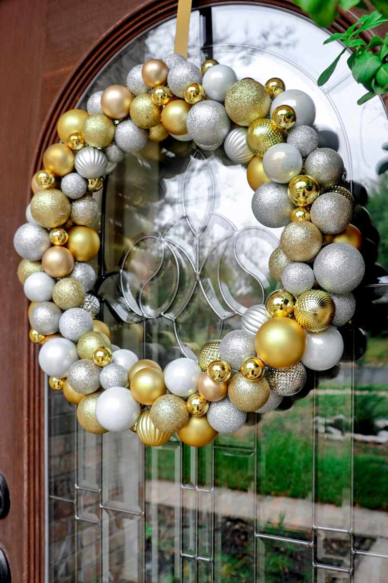 Minimalist Scandinavian entryway, white matte ornament wreath, light oak bench, subtle warm backlight.