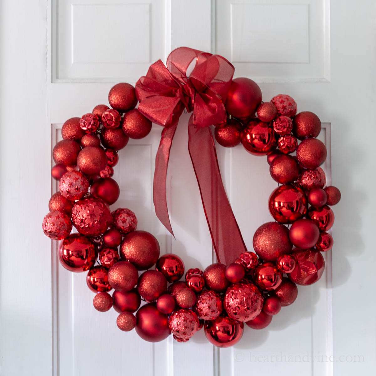 Retro midcentury living room, colorful ornament wreath, walnut credenza, warm glowing globe lights.