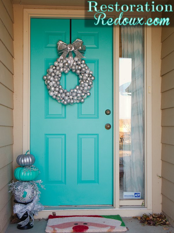Foyer entryway featuring copper ornament wreath, oak console table, brass sconce lighting, and muted green walls.