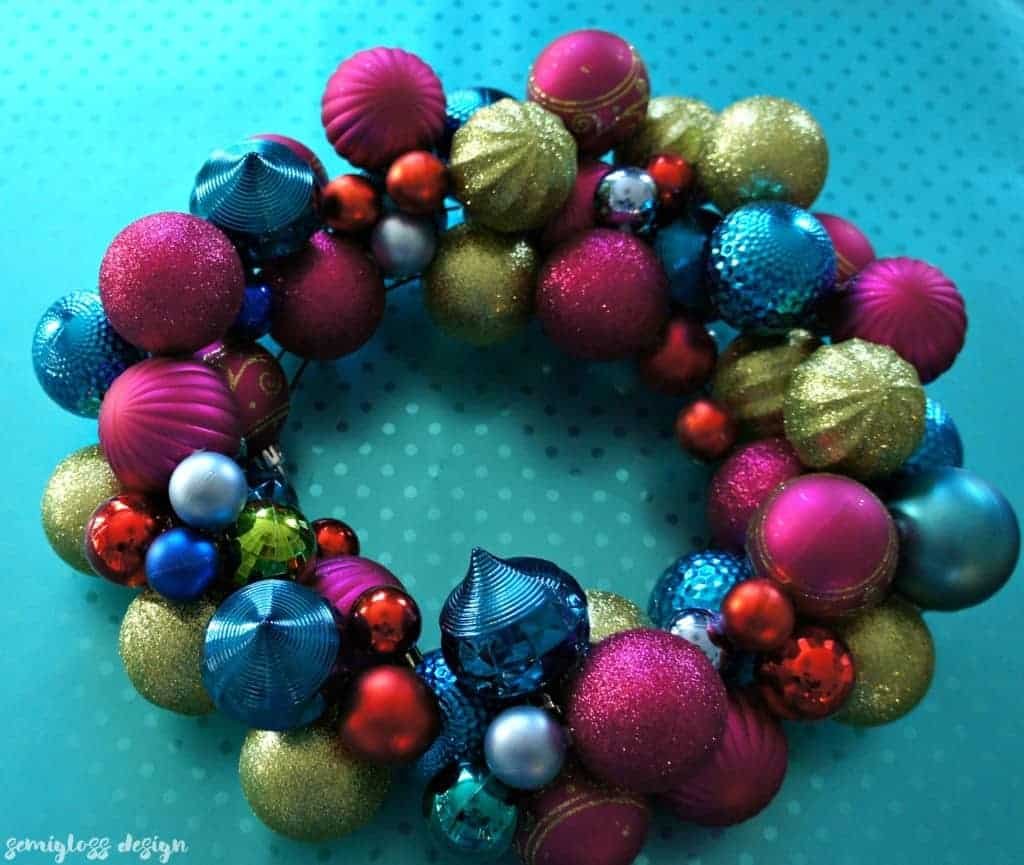 Rustic christmas ornament wreath with pinecones and red baubles on a natural oak timber door.