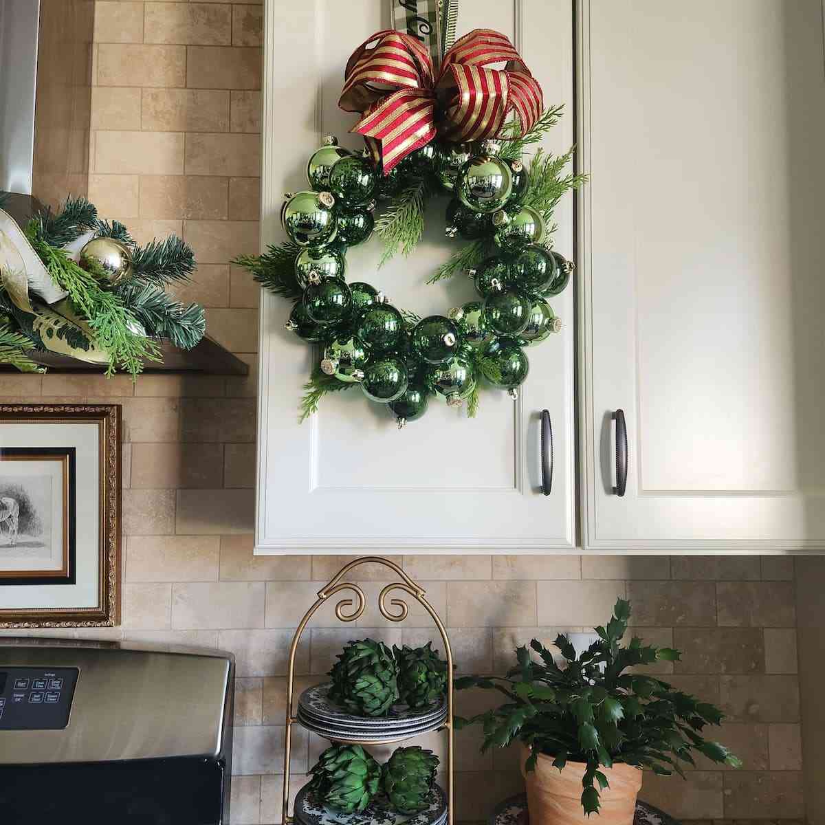 Champagne gold and rose blush christmas ornament wreath hanging on a muted grey foyer door.