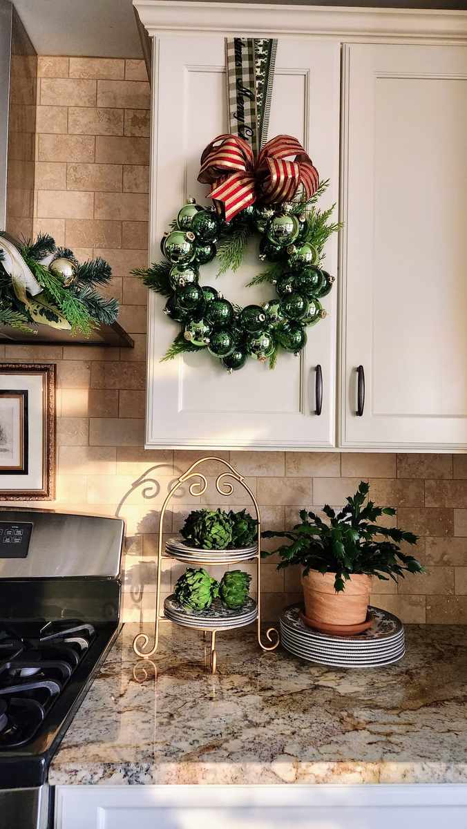 White and silver frosted christmas ornament wreath hanging on a navy blue front door.