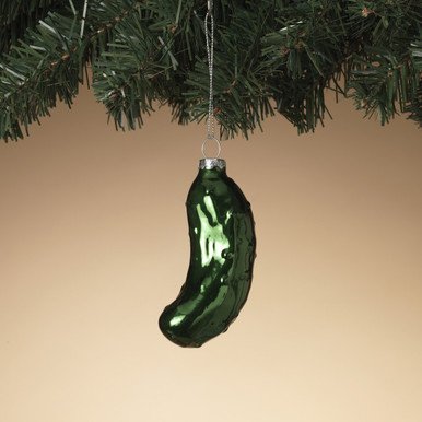 A clean Scandinavian inspired table centerpiece with a single hanging pickle ornament on a branch.