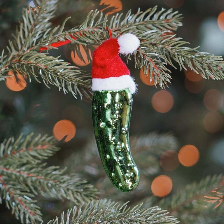 A small tabletop Christmas tree decorated with woodland creatures and a pickle ornament.