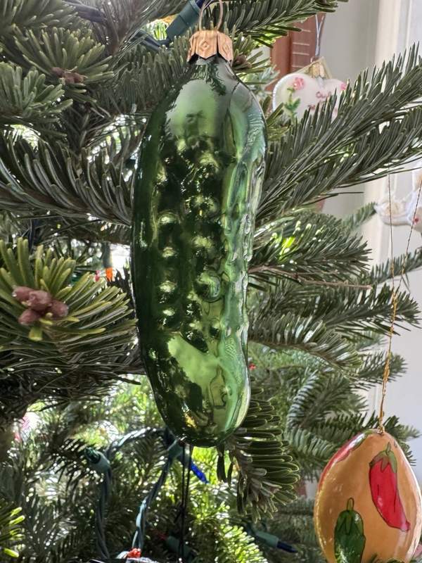 A luxurious Christmas tree decorated with gold, silver, and copper ornaments and a pickle.