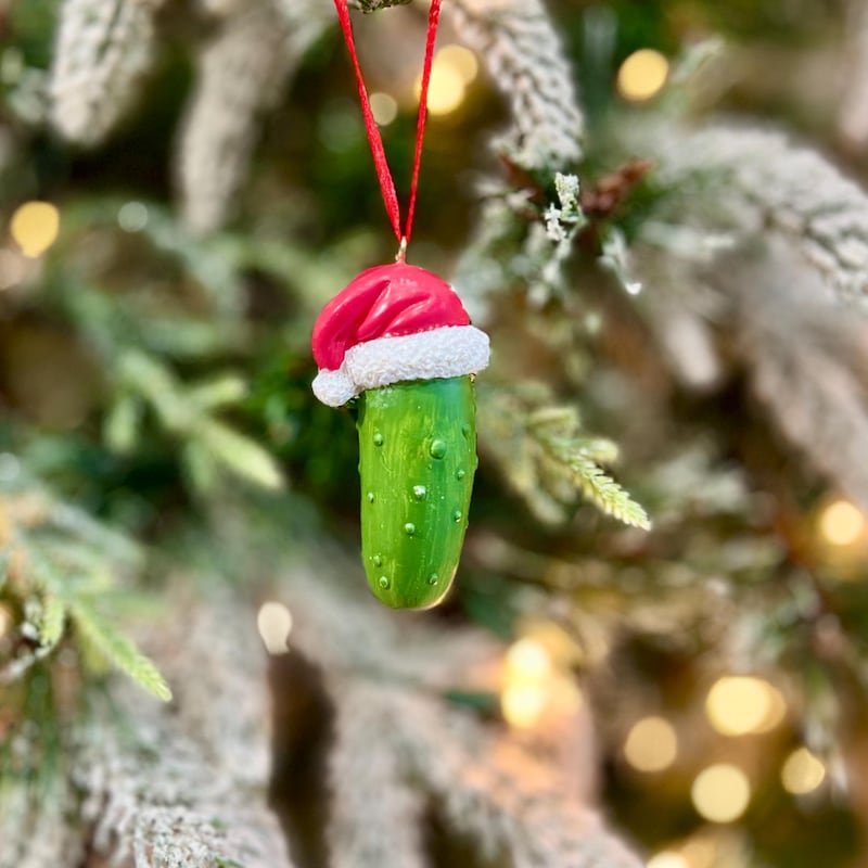 A comfortable reading chair with a festive throw blanket and a hidden pickle ornament.