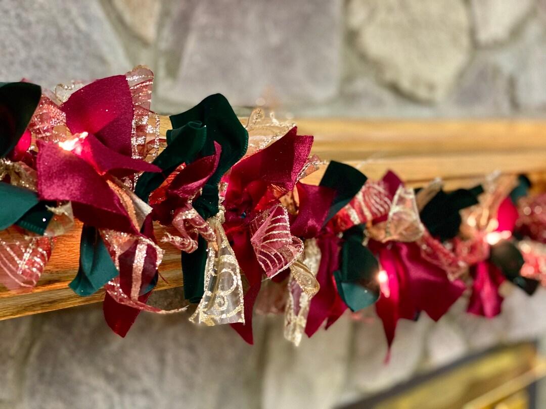 Entry hallway staircase with dark oak rail, pine garland, red velvet ribbon bows, and warm sconce lighting.