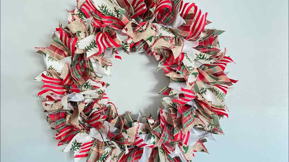 Dining room bay window displaying three boxwood wreaths suspended by champagne satin ribbons in soft sunlight.