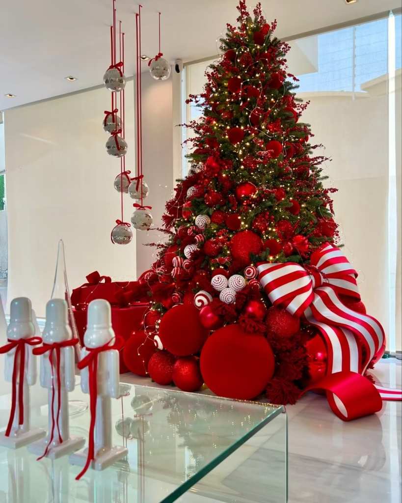 Sophisticated living room, deep red Christmas tree, gold accent ornaments, sleek leather sofa