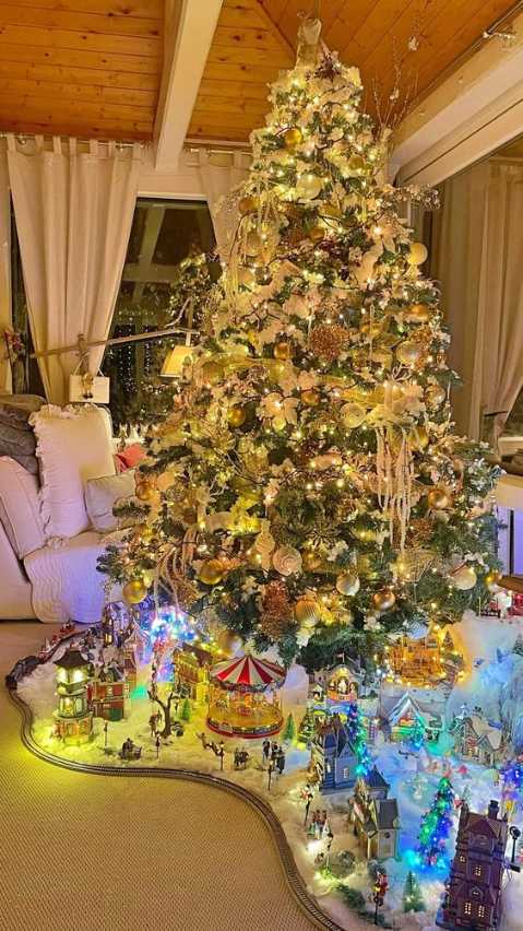 Living room, Christmas tree with miniature illuminated village, toy train set, soft ambient lighting