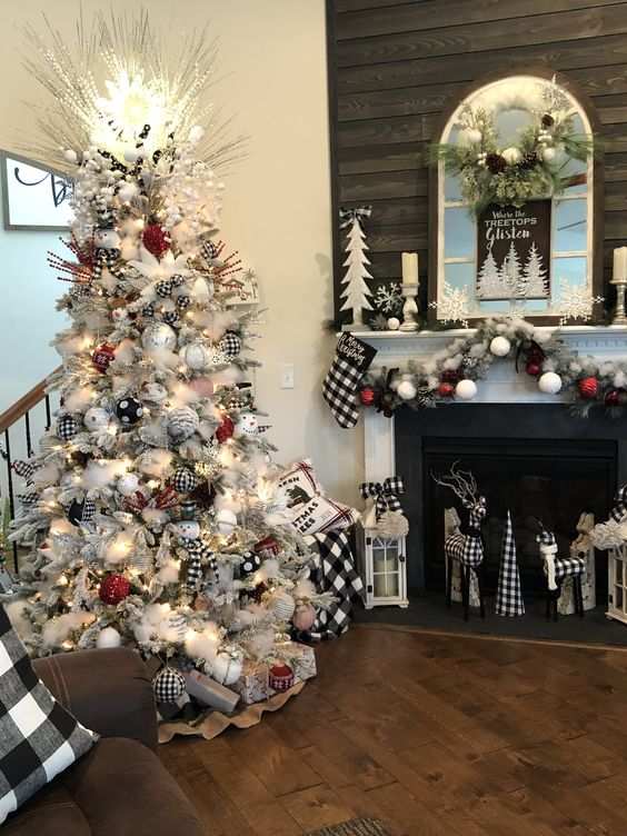Living room with fireplace, snowy Christmas tree, red and white ornaments, warm lighting