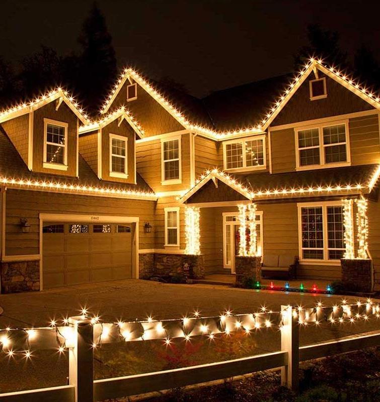 Warm white lights on roofline contrasting soft ambient porch lighting on brick house