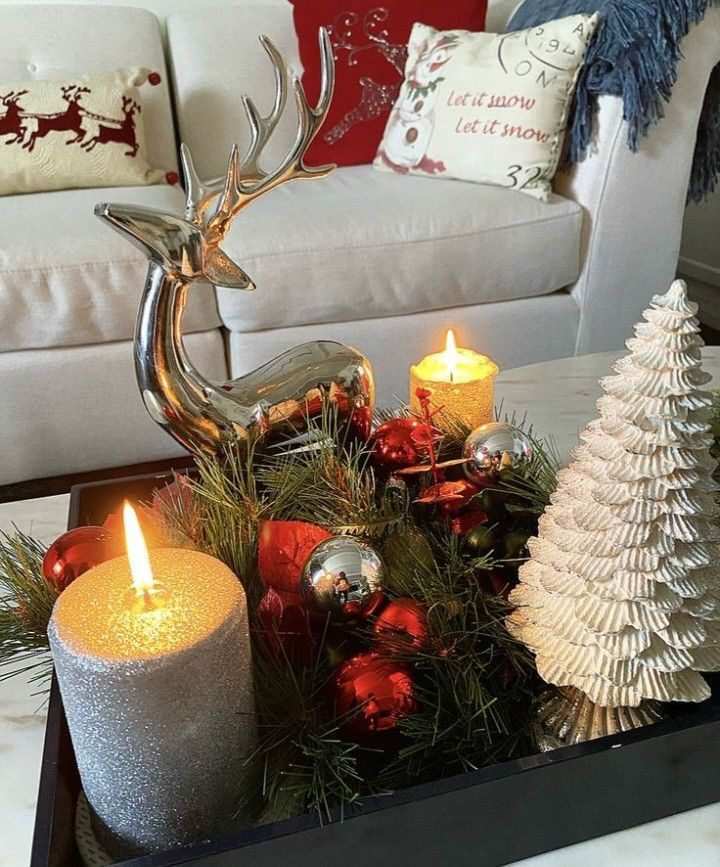 Plaid throw blanket folded on table with red and green candles and pinecones.