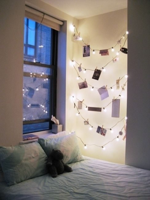 Warm white fairy lights with mini wooden clothespins pinning greeting cards along living room wall