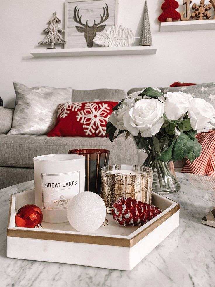 Coffee table displaying a cluster of red and gold pillar candles on a mirrored tray, accented with cinnamon sticks.