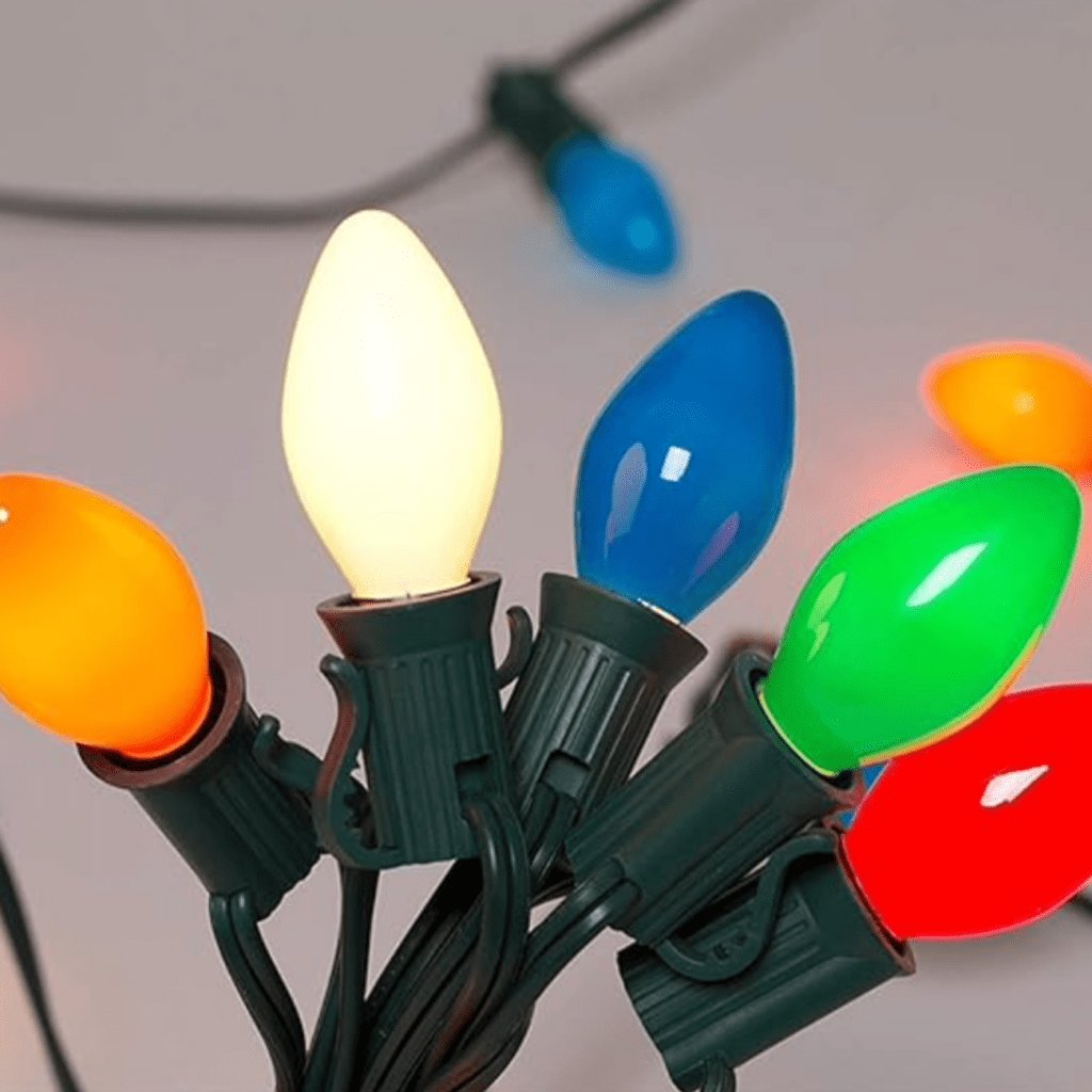 String of small colored mini lights in red, blue, green, and yellow hanging in a window.