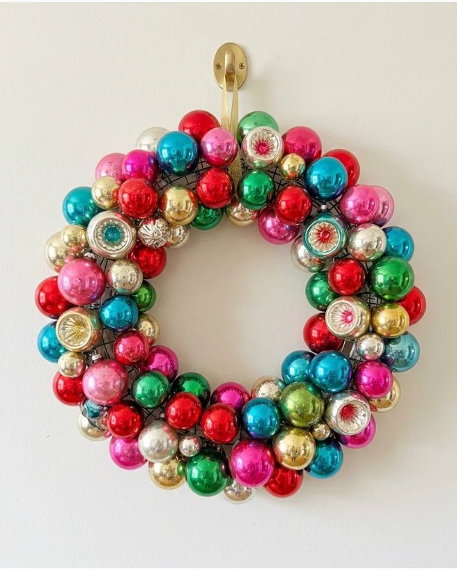 Colorful vintage ornament wreath on white wall with soft lighting