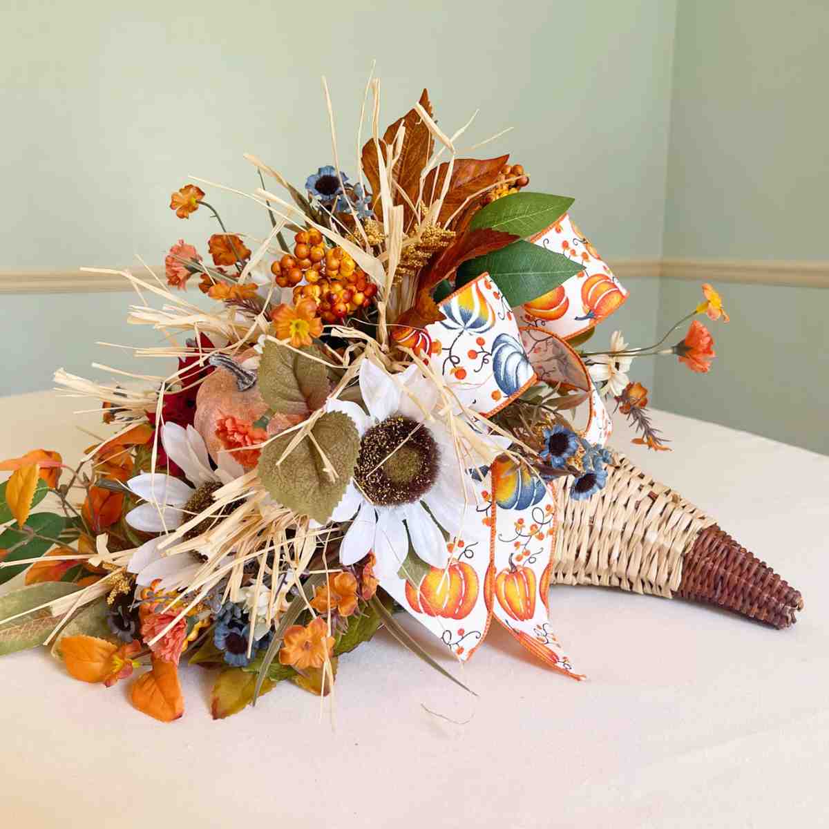 Sunroom coffee table, cornucopia bouquet, sunflowers, fall leaves, natural light, glass vase.