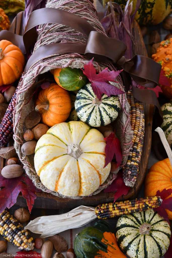 Close‑up on wooden tray, white pumpkin cornucopia, assorted gourds, soft studio lighting.