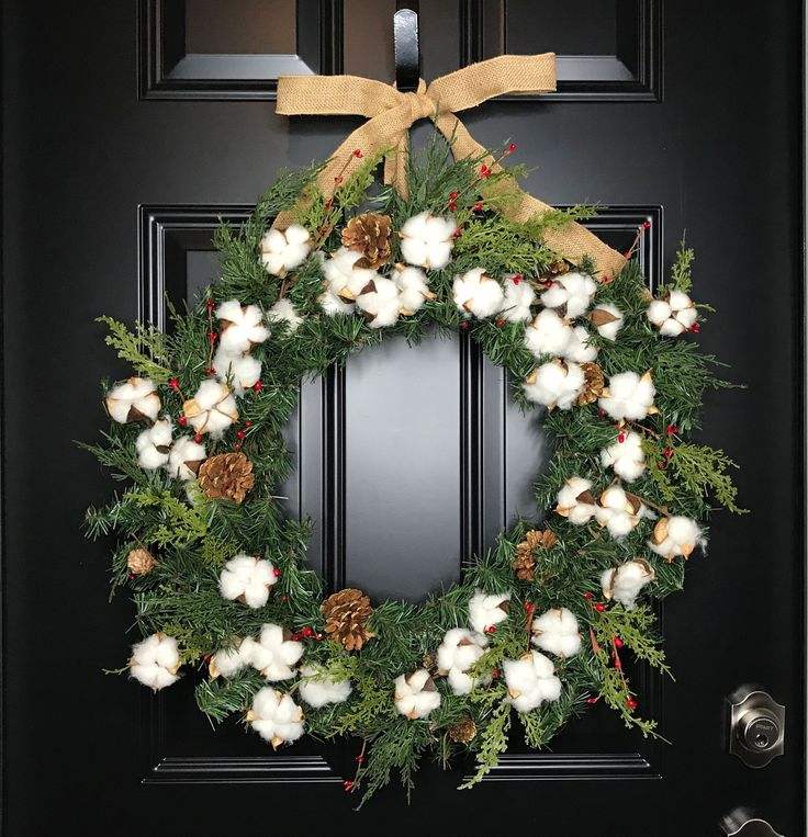 Neutral farmhouse front entryway featuring real cotton boll wreath on dark wooden door.