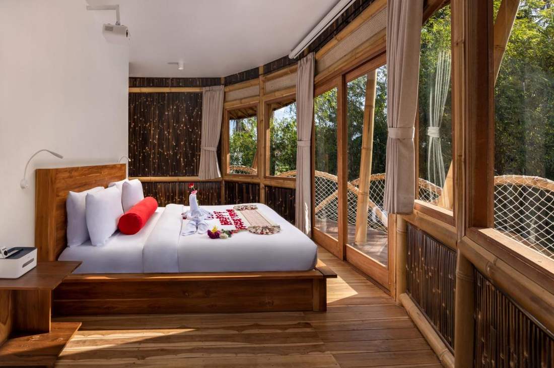 Modern master bedroom with oversized bouclé headboard, warm taupe bedding, ceramic table lamps, neutral carpet.