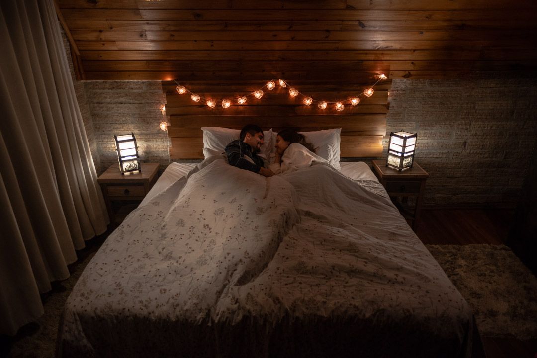Rustic couples bedroom featuring black wrought iron canopy bed, terracotta walls, warm globe lamps.