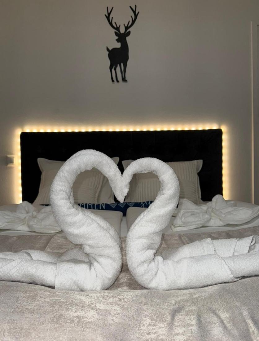 Modern couples bedroom with textured white boucle bed travertine nightstands matte black sconces and warm lighting