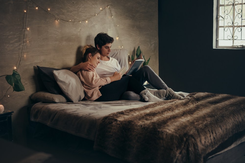 Industrial couples bedroom with exposed red brick wall black iron bed warm Edison bulb soft grey linens