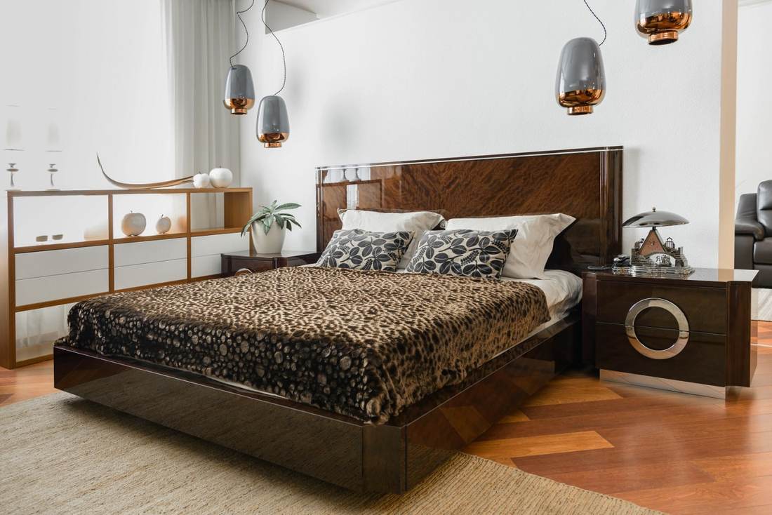High-end bedroom with upholstered headboard, crisp white linens, glass side tables, and recessed spotlights.