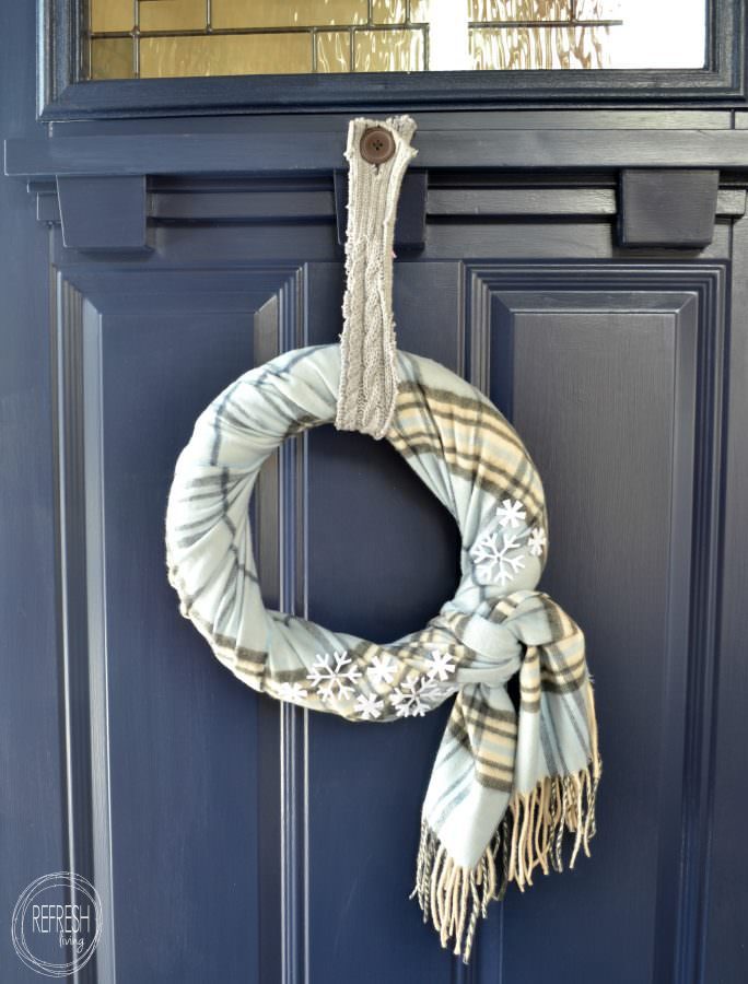 Heather grey knitted scarf wreath featuring long cascading fringe on a rustic reclaimed barnwood door