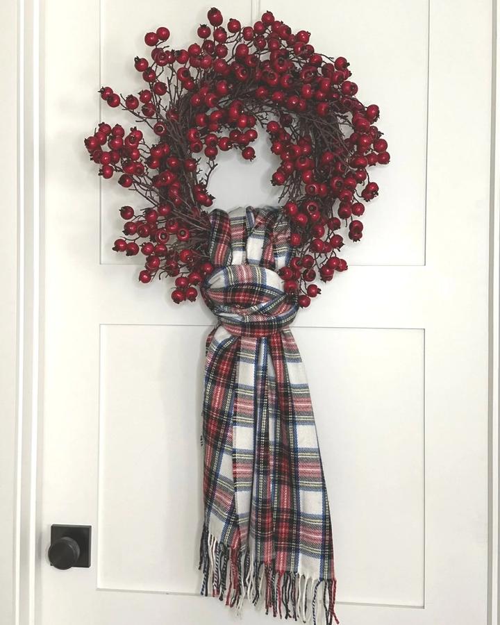 Earthy rust terracotta ribbed scarf wreath with dried pampas grass on a warm oak door