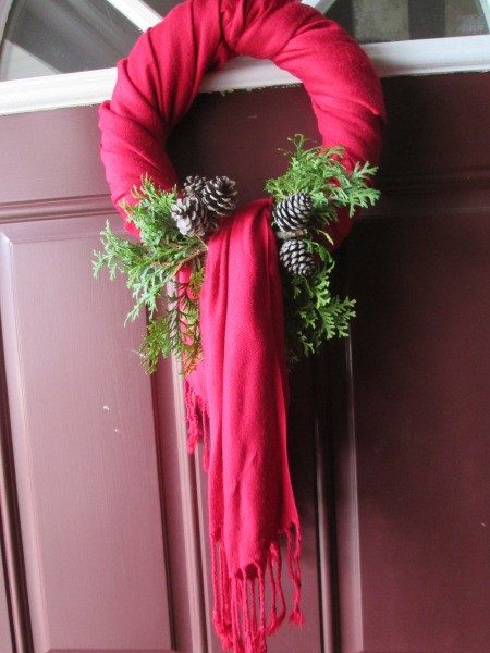 Fair isle pattern wool scarf wreath adorned with wooden bells on a dark green door