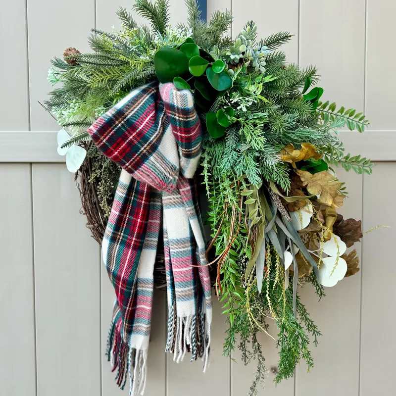 Cozy diy winter scarf wreath on entryway brass mirror with wooden console table and warm lighting