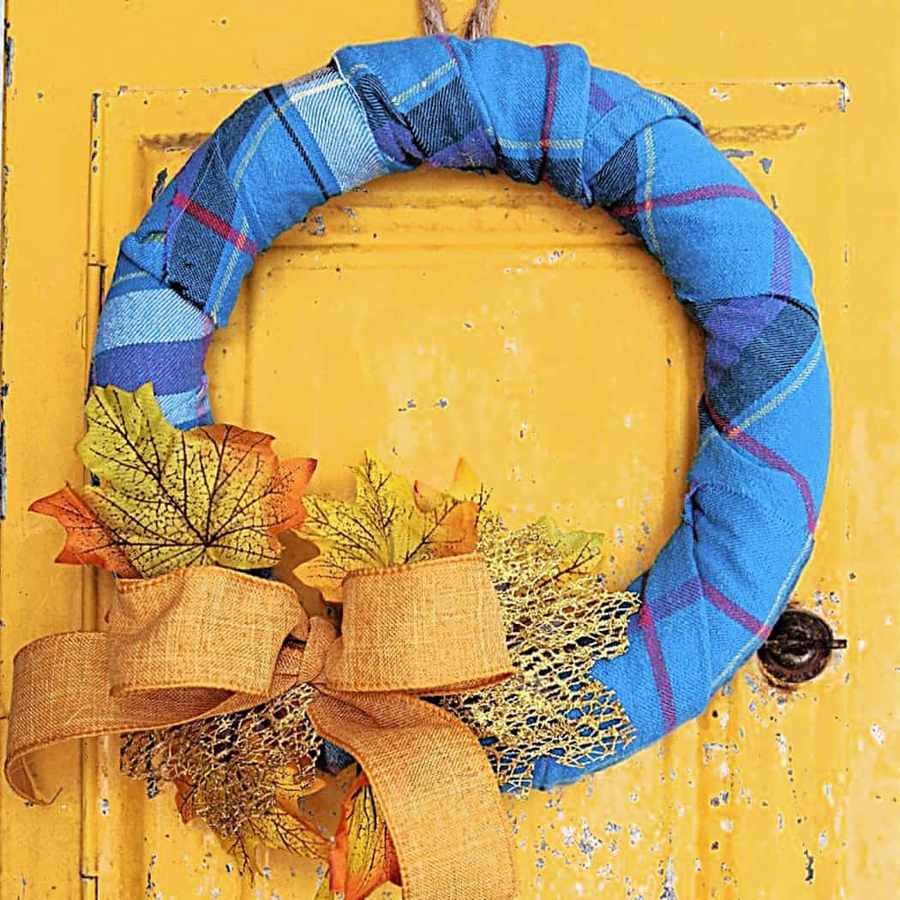 Cream chunky boucle scarf wreath mounted above living room stone fireplace with warm golden candlelight