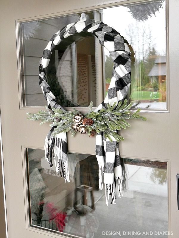 White cable knit scarf wreath hanging on dining wall with Scandinavian wooden table and warm lighting