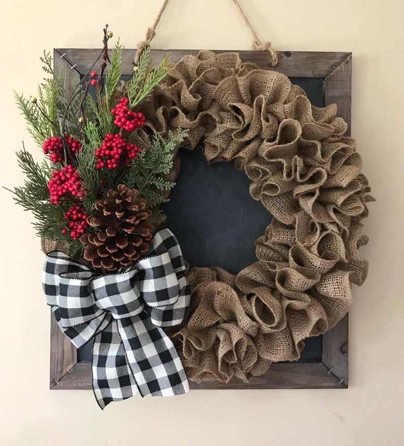 Dusty rose chenille scarf wreath hanging above guest room bed with white duvet and warm lighting